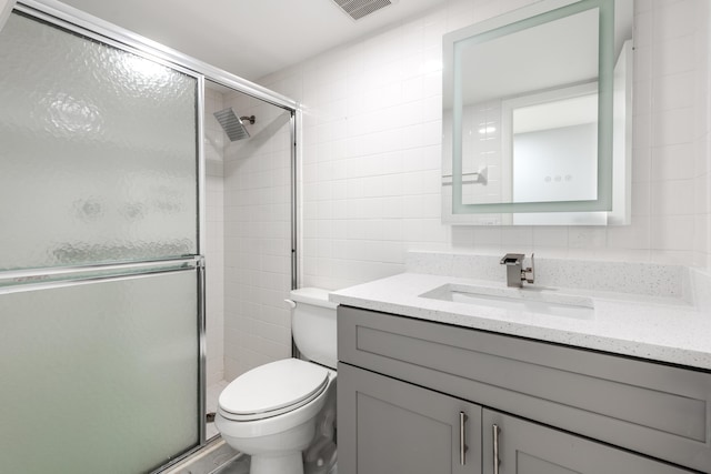 bathroom with tile walls, backsplash, vanity, an enclosed shower, and toilet