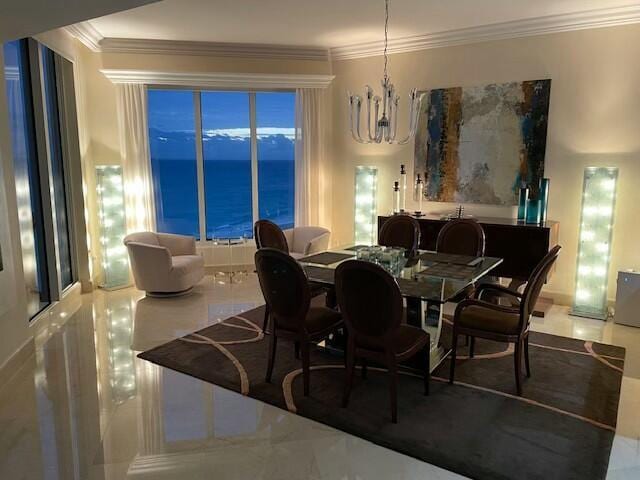 dining space with a notable chandelier, crown molding, and a water view