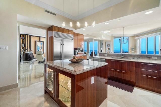 kitchen featuring sink, a center island, ornamental molding, a notable chandelier, and pendant lighting