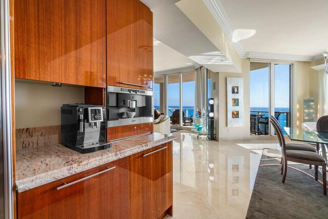 kitchen with stainless steel oven, a water view, crown molding, light stone countertops, and a healthy amount of sunlight