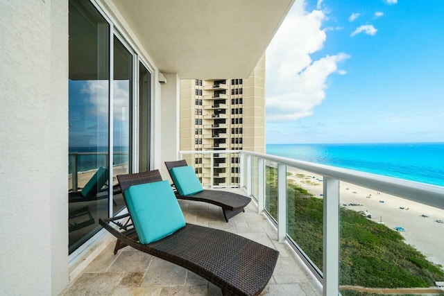 balcony with a water view and a view of the beach