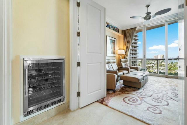 living area with light tile patterned floors, a wall of windows, ceiling fan, ornamental molding, and beverage cooler