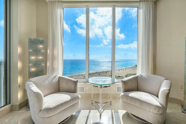 living area featuring a view of the beach and a water view