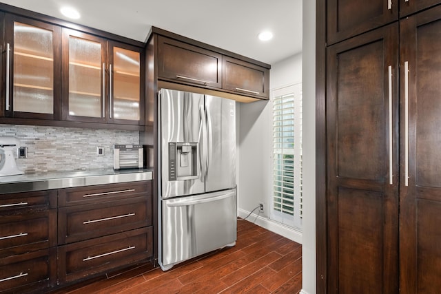 kitchen featuring dark wood-type flooring, stainless steel fridge, stainless steel counters, backsplash, and dark brown cabinetry