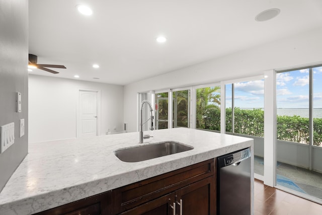 kitchen with a healthy amount of sunlight, dishwasher, sink, and light stone countertops