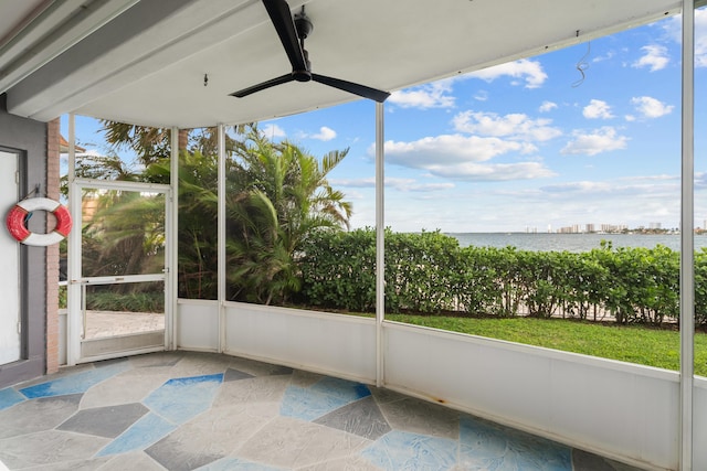 unfurnished sunroom featuring ceiling fan and a water view