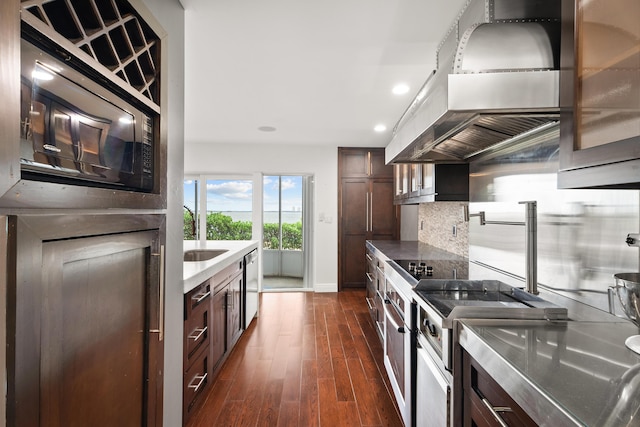 kitchen featuring dark brown cabinetry, stainless steel dishwasher, dark hardwood / wood-style floors, island exhaust hood, and backsplash