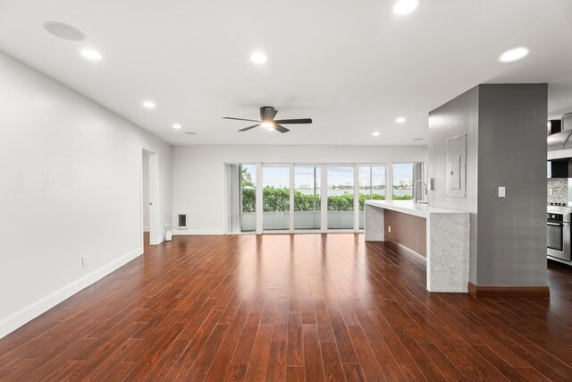 unfurnished living room with sink, dark hardwood / wood-style floors, and ceiling fan