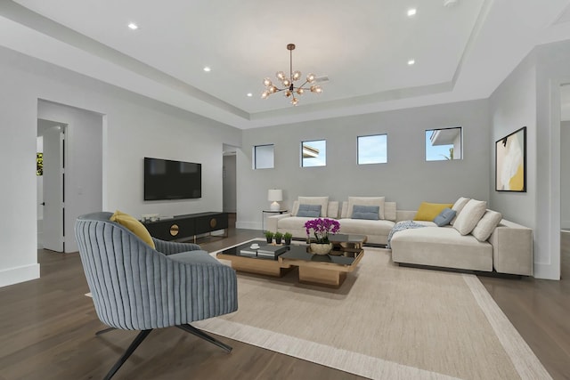 living room with hardwood / wood-style floors, a raised ceiling, and a chandelier