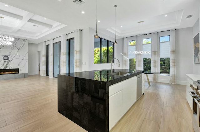 kitchen with a large island, sink, pendant lighting, a fireplace, and white cabinets