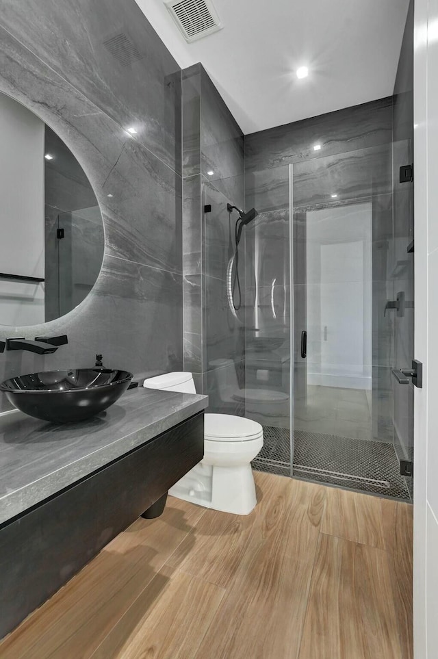 bathroom with walk in shower, vanity, toilet, and tile walls