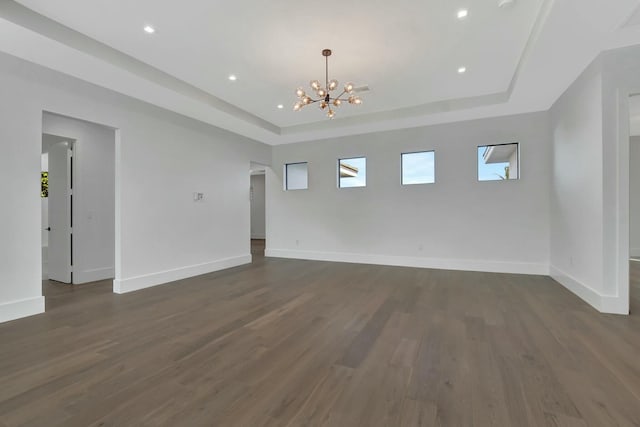 unfurnished room with dark wood-type flooring, a notable chandelier, and a tray ceiling