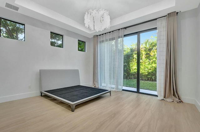 unfurnished bedroom with light hardwood / wood-style flooring, a notable chandelier, multiple windows, and access to outside