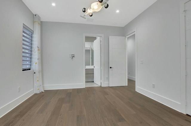 unfurnished bedroom featuring connected bathroom and hardwood / wood-style floors