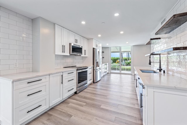 kitchen with white cabinetry, sink, light hardwood / wood-style floors, and appliances with stainless steel finishes