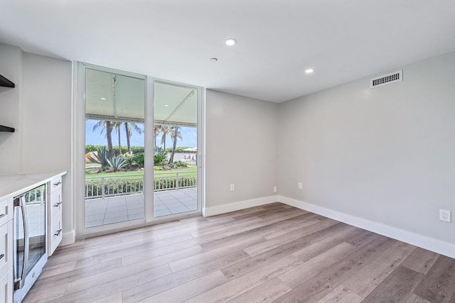 interior space with expansive windows, light hardwood / wood-style floors, and wine cooler