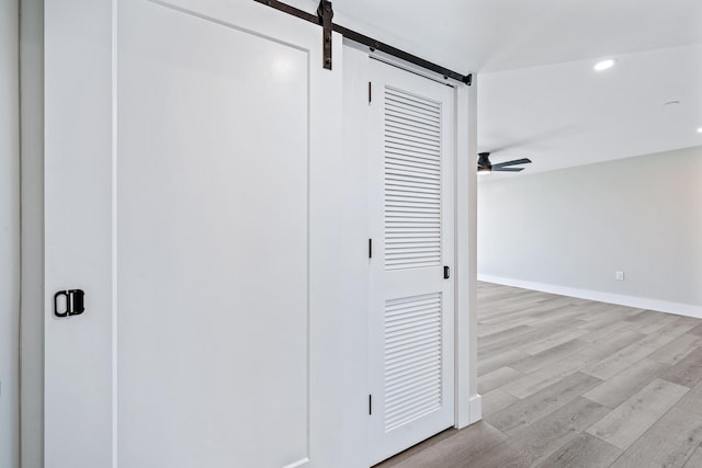 hall with a barn door and light hardwood / wood-style flooring