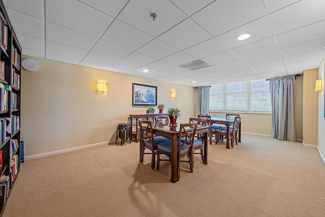 carpeted dining area with a drop ceiling