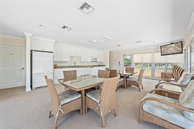 carpeted dining space featuring crown molding and sink