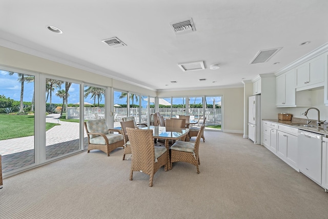 carpeted dining room featuring crown molding and sink