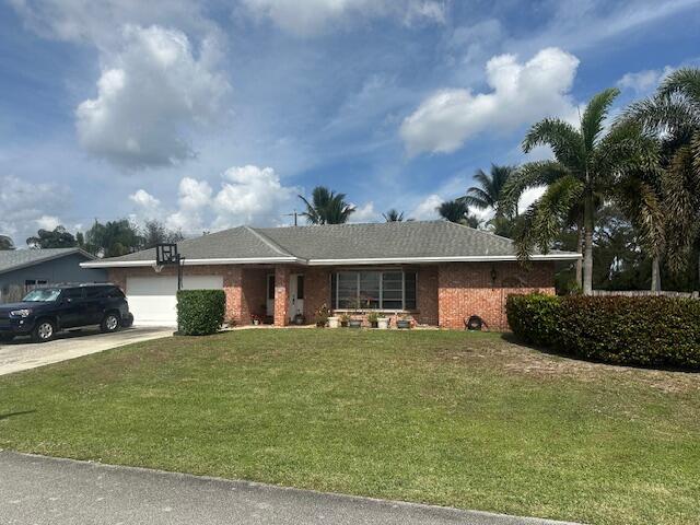 single story home with a garage, brick siding, concrete driveway, and a front yard