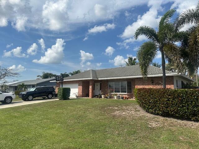 ranch-style house featuring a garage, concrete driveway, and a front yard