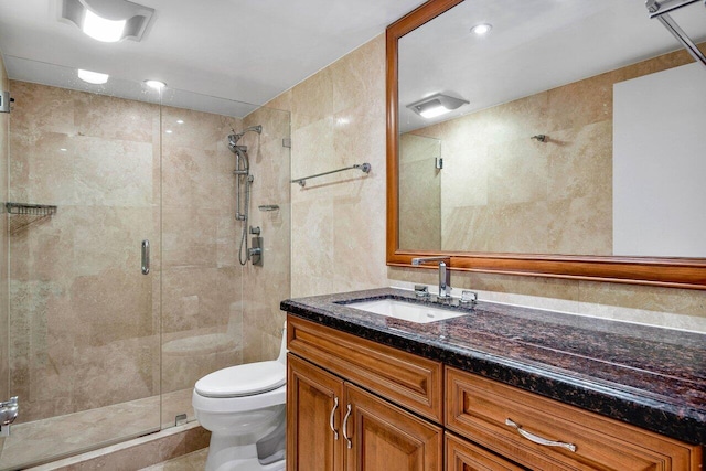 bathroom featuring a shower with door, vanity, and toilet