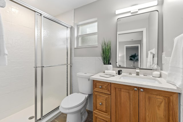 bathroom featuring walk in shower, vanity, toilet, and tile walls