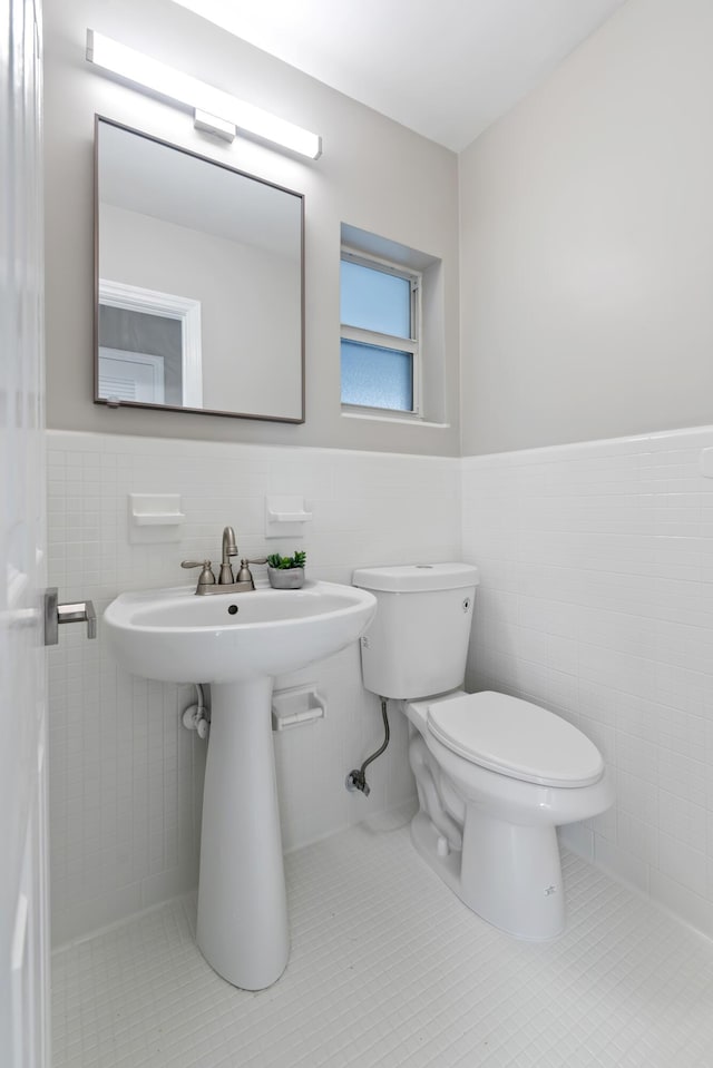 bathroom with tile patterned flooring, sink, tile walls, and toilet