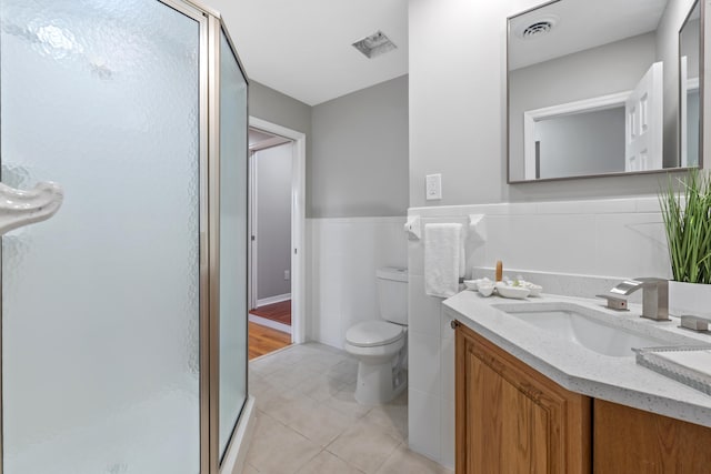 bathroom featuring tile walls, tile patterned flooring, vanity, toilet, and a shower with door