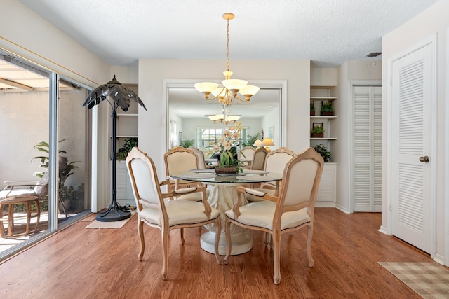 dining space featuring an inviting chandelier, wood-type flooring, and a textured ceiling