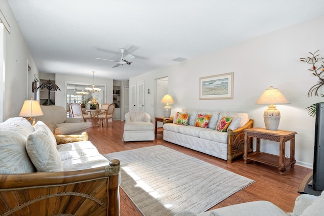 living room featuring ceiling fan with notable chandelier and light hardwood / wood-style flooring