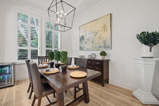 dining area featuring ornamental molding, beverage cooler, and light hardwood / wood-style flooring