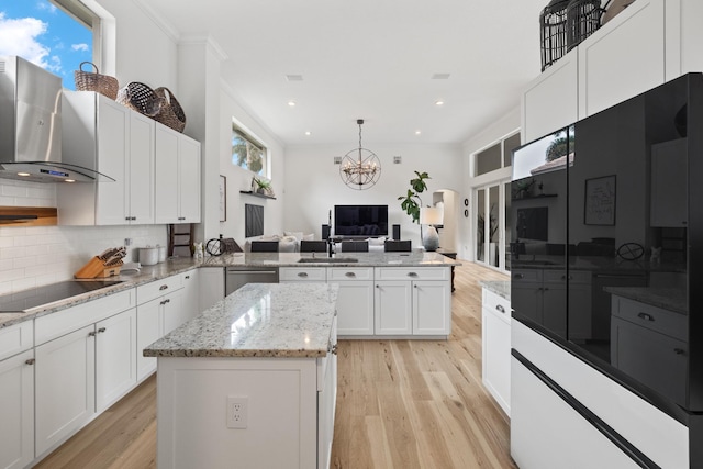 kitchen featuring wall chimney exhaust hood, white cabinetry, tasteful backsplash, a center island, and black electric stovetop