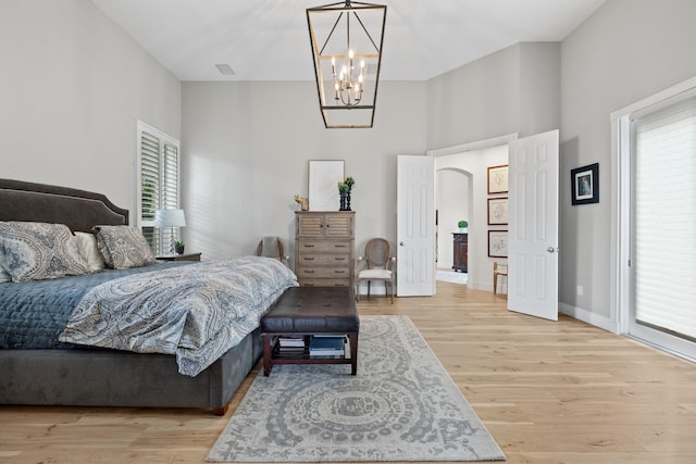 bedroom featuring an inviting chandelier, light hardwood / wood-style floors, and multiple windows