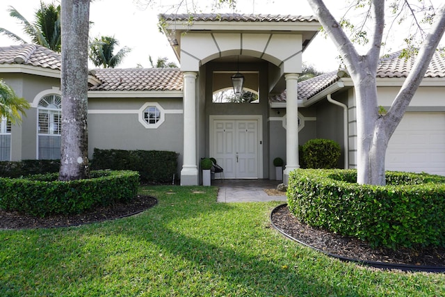 property entrance featuring a garage and a lawn