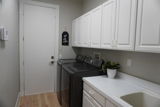 washroom with light hardwood / wood-style floors, cabinets, and washing machine and clothes dryer