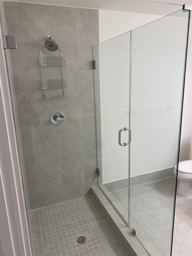 bathroom with an enclosed shower, tile patterned floors, and toilet