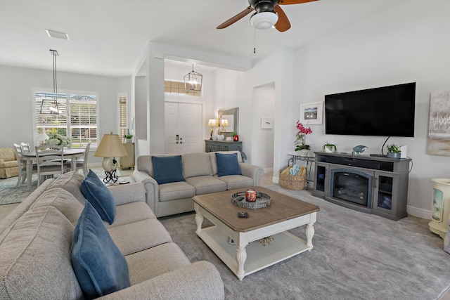 carpeted living room with a fireplace and ceiling fan