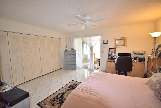 bedroom with ceiling fan, a closet, a textured ceiling, and light tile patterned floors