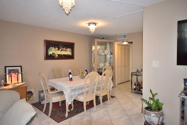 dining area with light tile patterned floors, a chandelier, and a textured ceiling