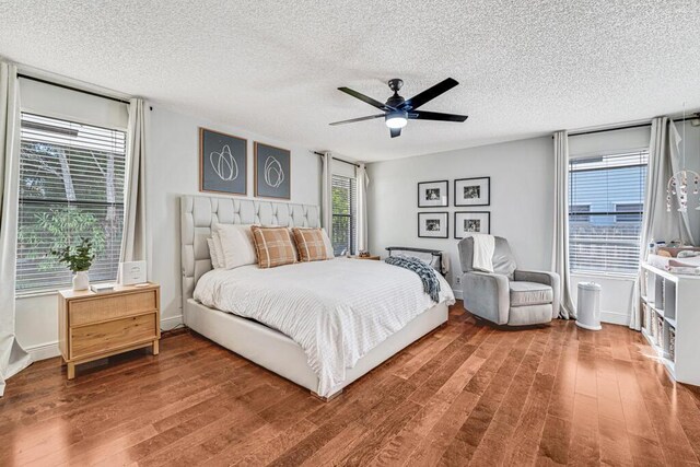 bedroom with ceiling fan, hardwood / wood-style floors, and a textured ceiling