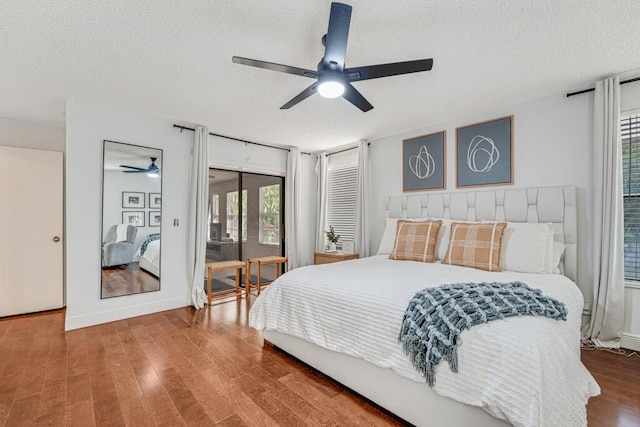 bedroom featuring hardwood / wood-style floors, access to outside, a textured ceiling, and ceiling fan