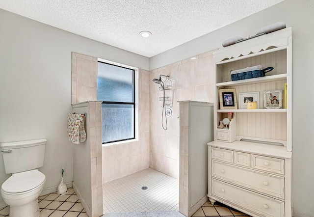 bathroom featuring a tile shower, a wealth of natural light, a textured ceiling, and toilet