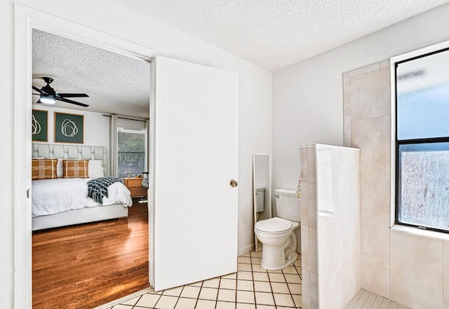 bathroom with ceiling fan, a tile shower, a textured ceiling, and toilet