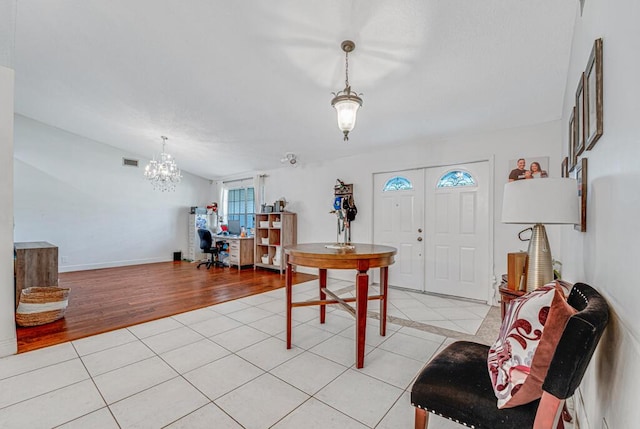 tiled entryway with vaulted ceiling and a chandelier