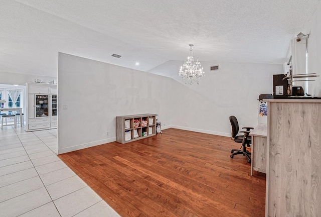 office with vaulted ceiling, a chandelier, a textured ceiling, and light wood-type flooring