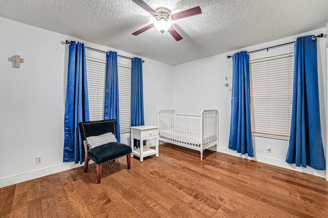 bedroom featuring hardwood / wood-style flooring, ceiling fan, and a textured ceiling