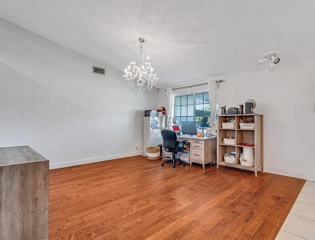 office featuring light hardwood / wood-style floors, a chandelier, and a textured ceiling