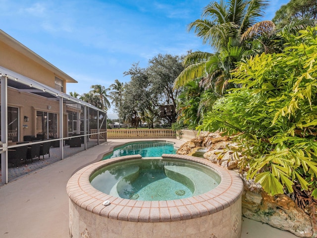 view of swimming pool with an in ground hot tub, a lanai, and a patio area